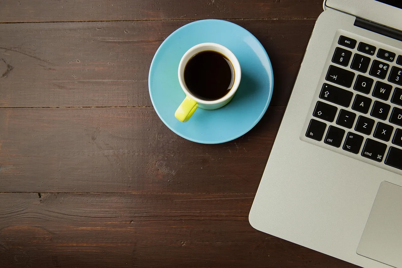 coffee, coffee cup, cup, saucer, laptop, computer, macbook, designer, overhead, desk, workspace, wood, brown computer, brown coffee, brown laptop, brown desk, brown cup. How to implement web design agency time tracking